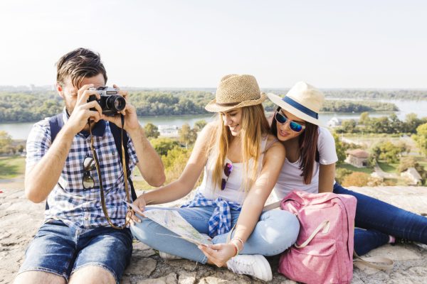 man-taking-photo-camera-near-his-female-friends-looking-map